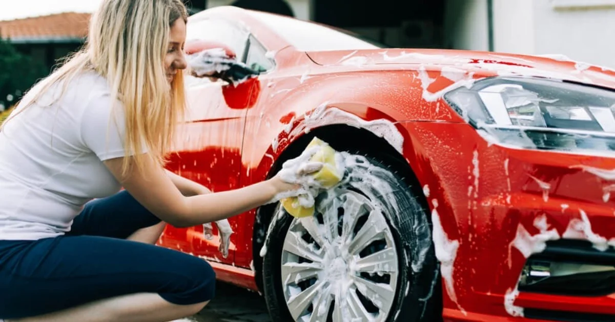 a young woman cleaning the wheels of her car with a sponge