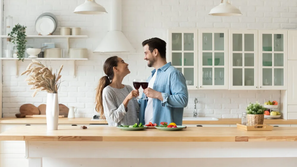 man and woman at home smiling with a glass of wine