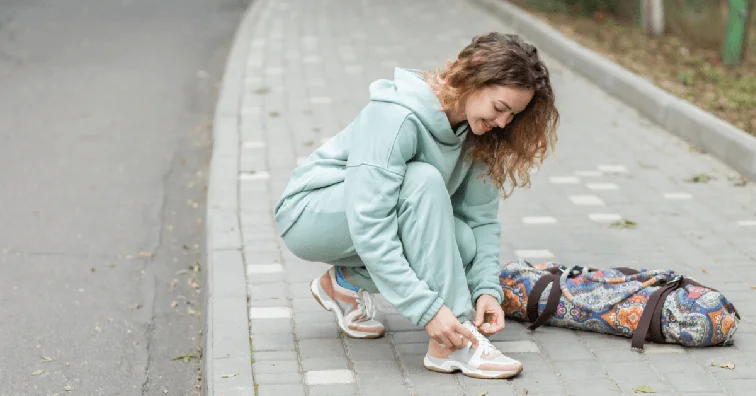 Young woman in activewear tying her laces in the street