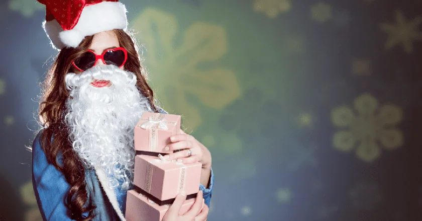A woman holding Christmas presents disguised in Santa's beard and a pair of sunglasses