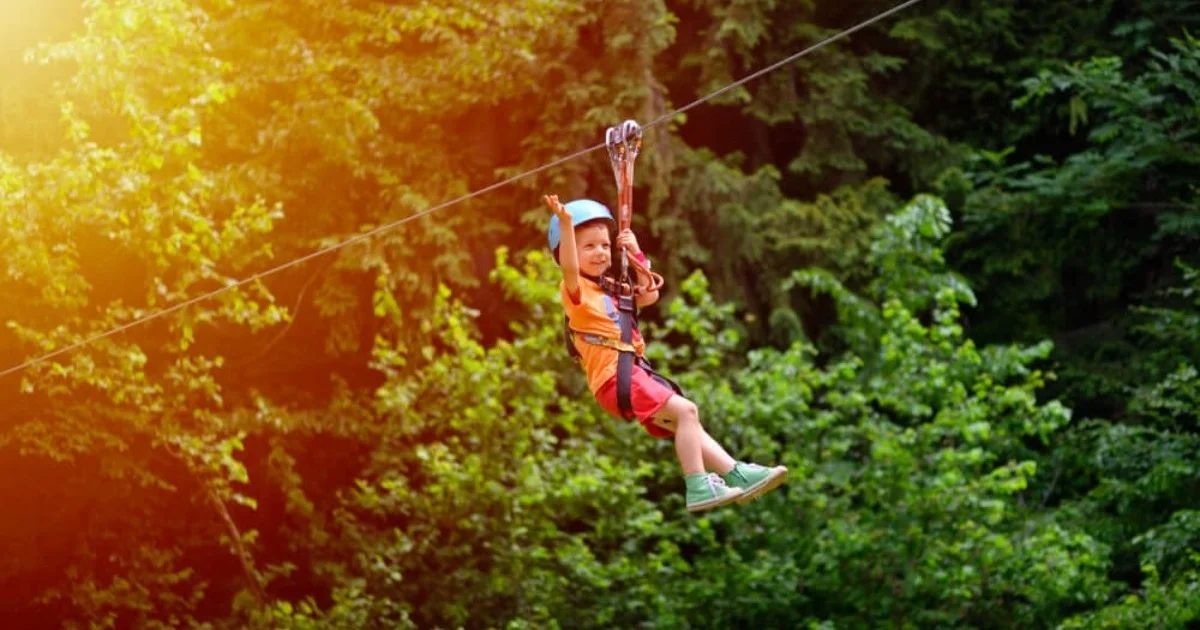 A young boy zip lining through some woods