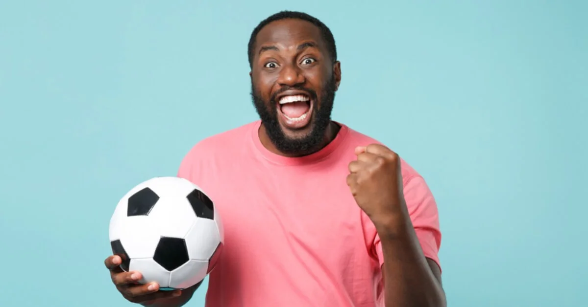 a man holding a football looking happy and cheering