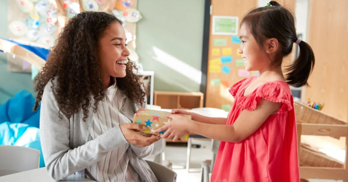 a small child giving their teacher a gift
