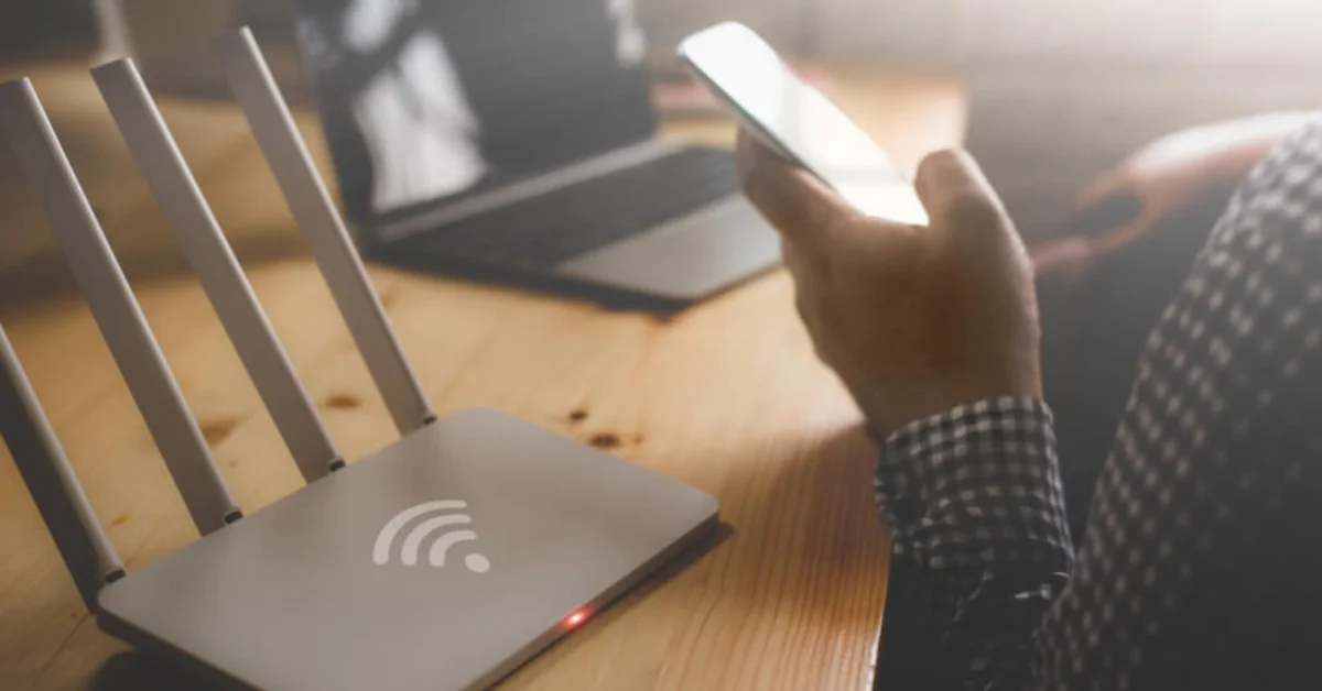 a man holding a phone next to a broadboand box