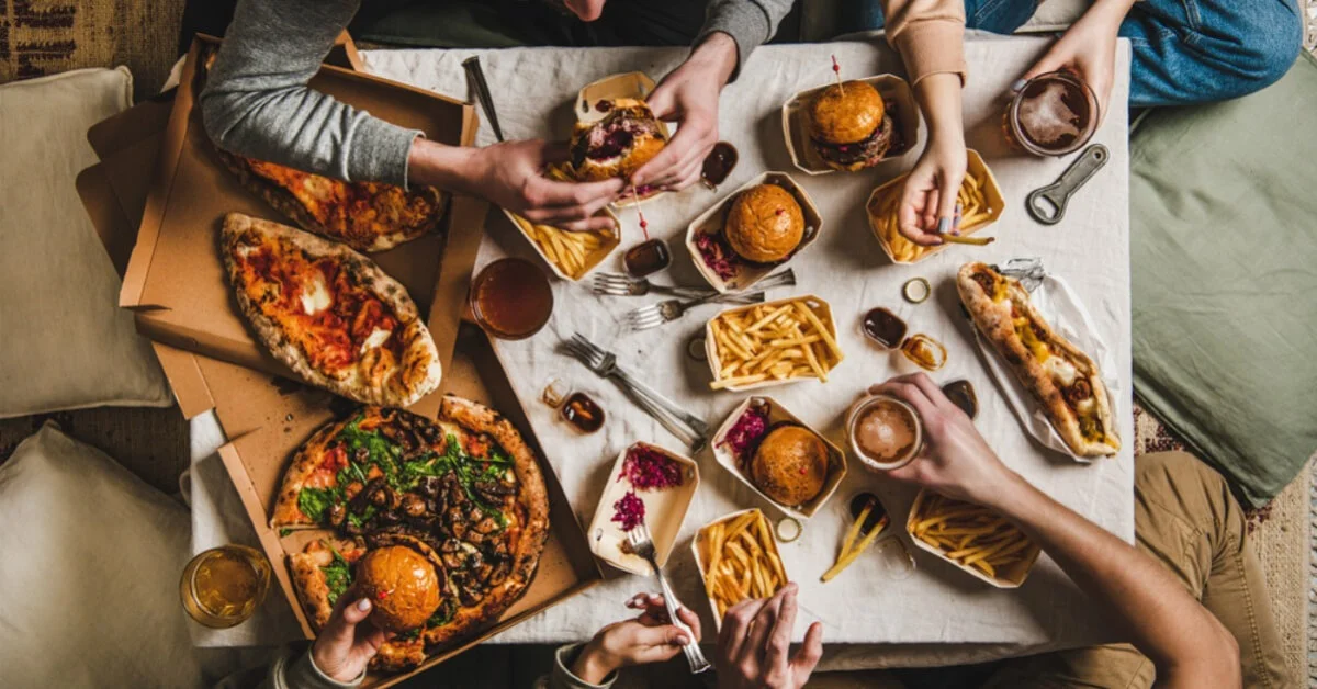 friends eating from a table full of takeaway food