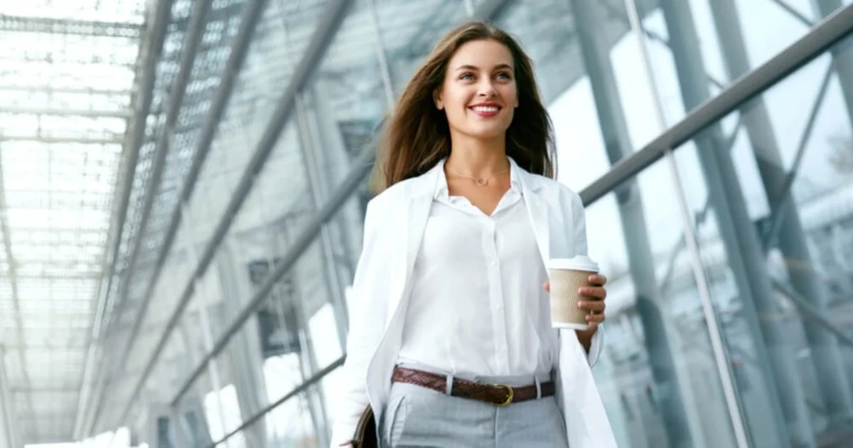 a smart looking young woman walking with a coffee