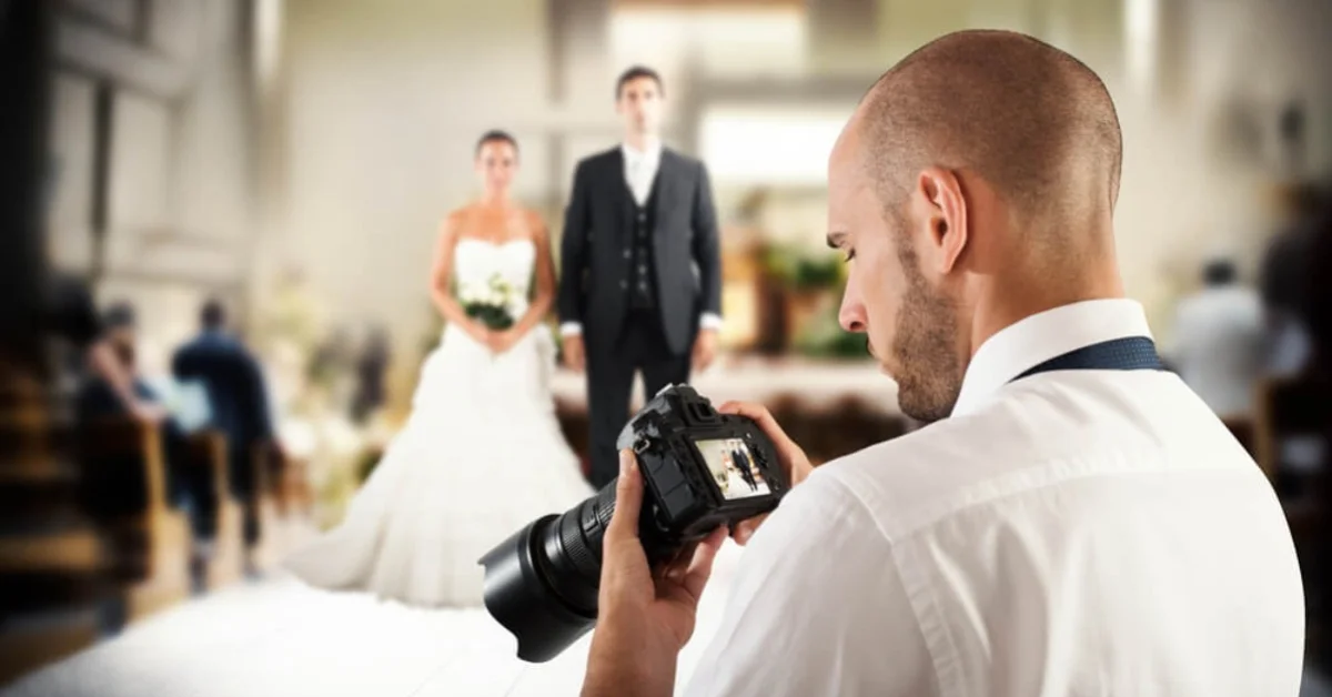 a male photographer taking photos as new married couple walk down the aisle