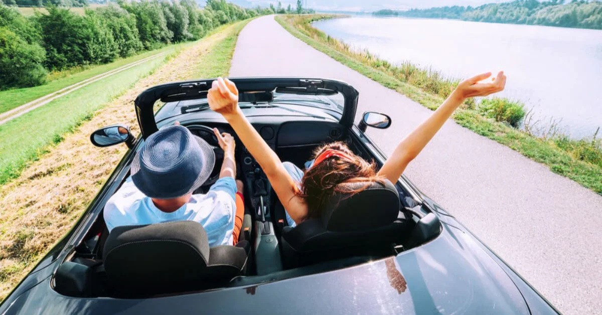 a happy couple in a convertible car on holiday