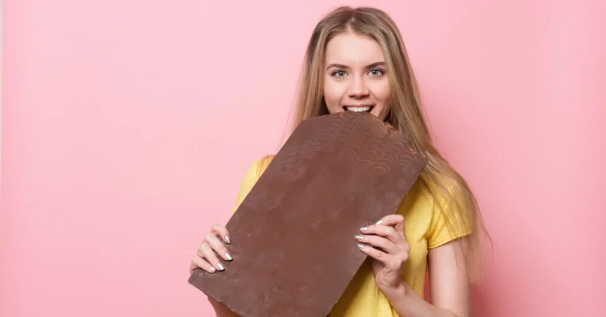 a young woman holding a huge bar of chocolate