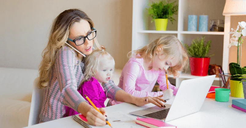 A busy mum multi tasking, on a laptop and phone with two children