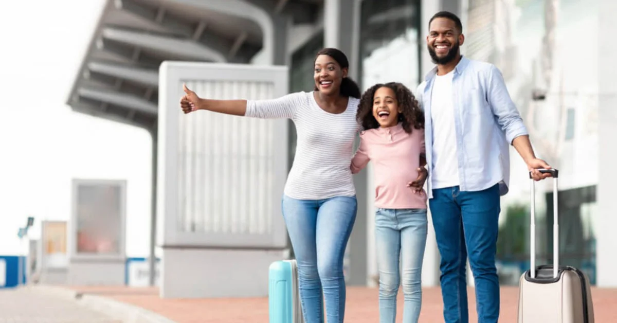 a happy family flagging down their taxi at the airport