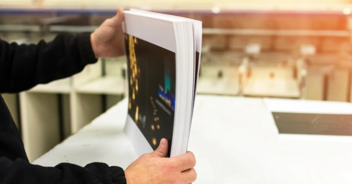 a man holding a brochure on a table