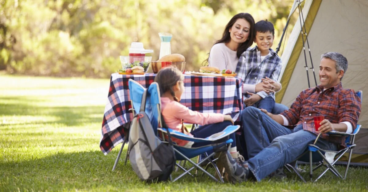 a family smiling and laughing outside of their tent