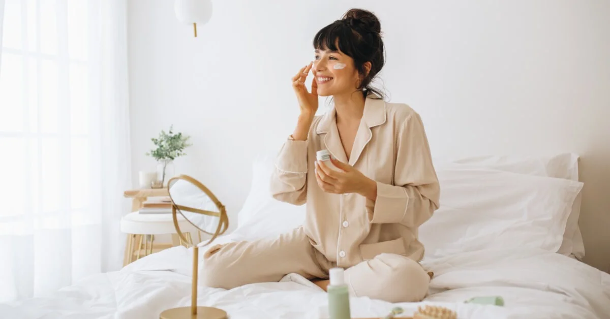 a woman smiling applying skincare