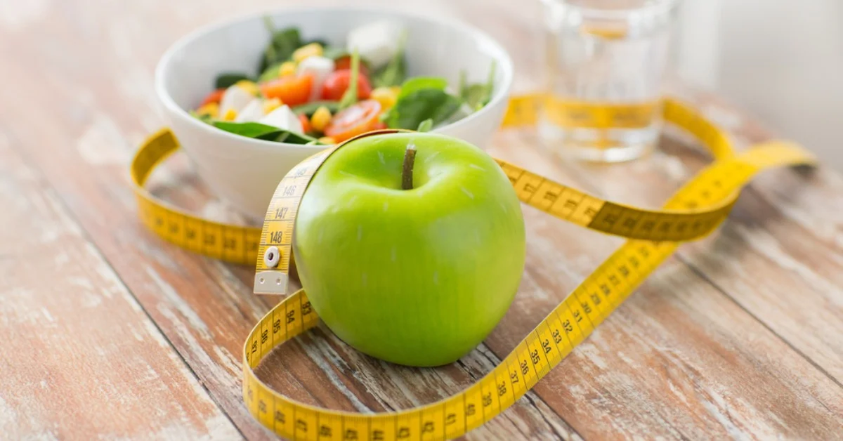 an apple and salad bowl with a tape measure