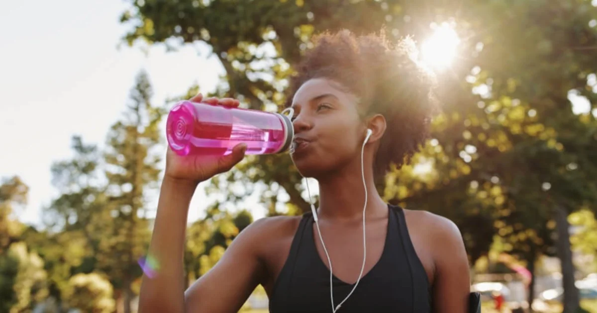 a young woman drinking from a bottle on a run