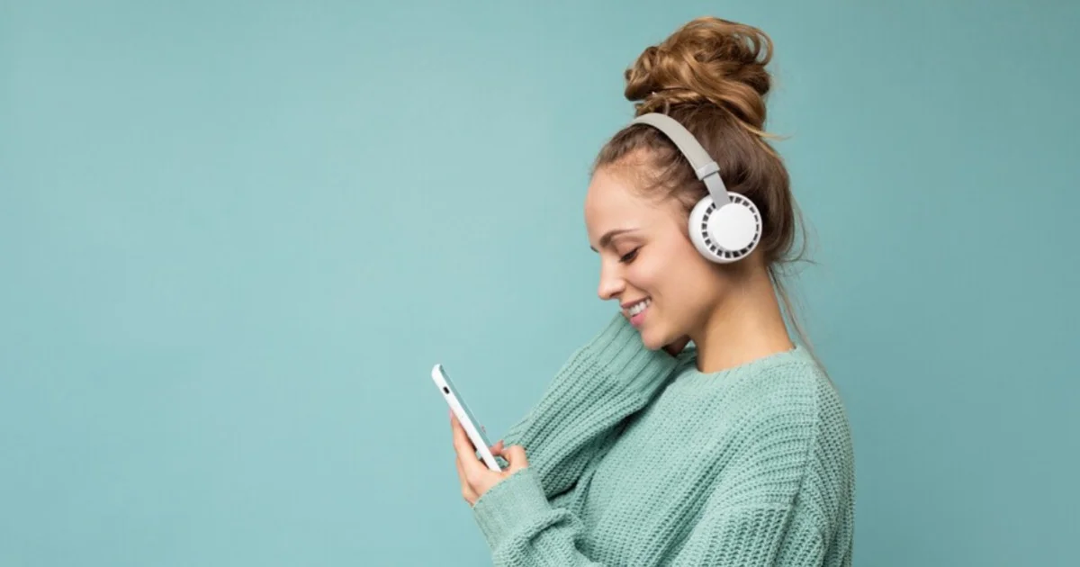 a young woman smiling at her phones with headphones on