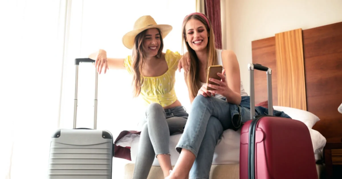 two girls smiling in their hotel room with their luggage