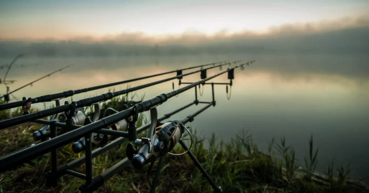 fishing rods laying over a lake over sunrise