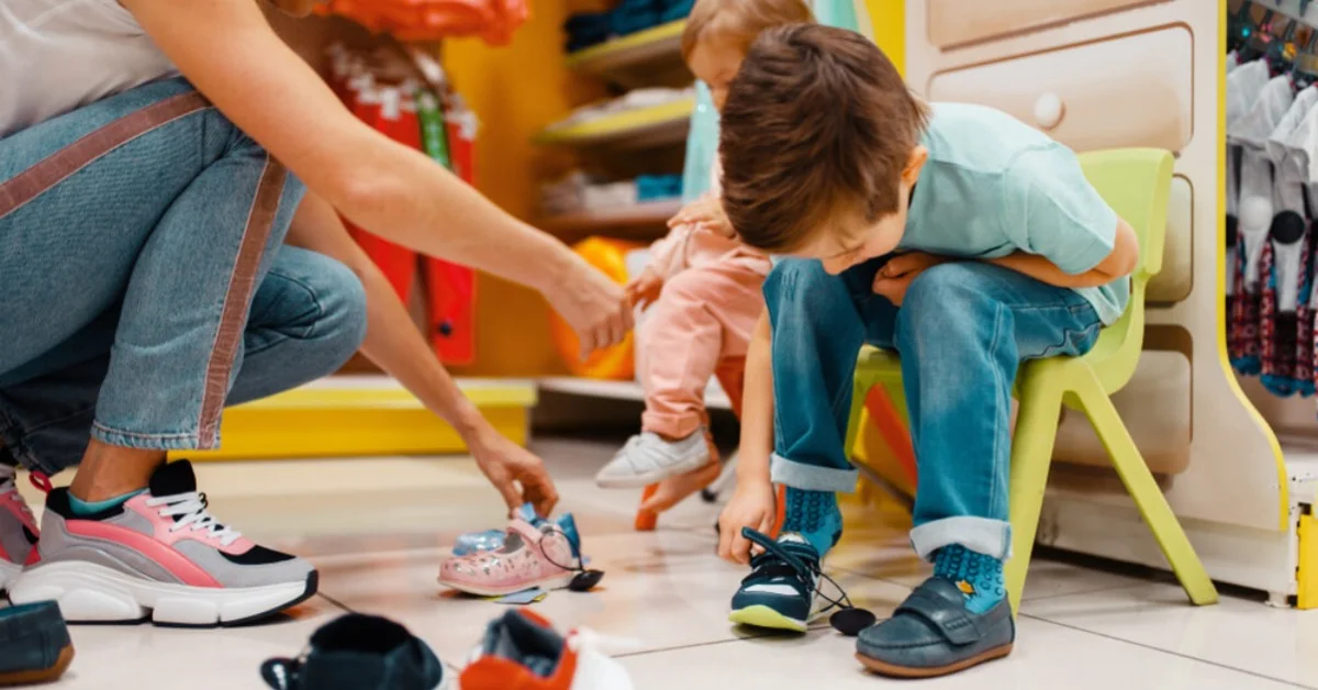 a mum helping her young boy try some shoes on in a shop